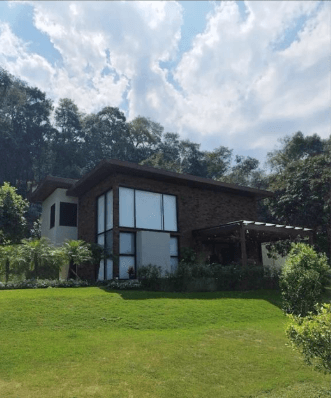 Casa finalizada com fachada de tijolos aparentes, grandes janelas e jardim