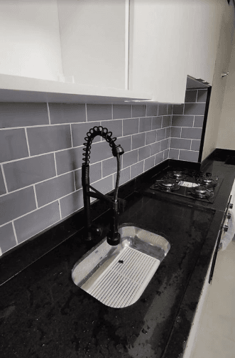 Cozinha com revestimento cerâmico cinza e bancada de granito preto