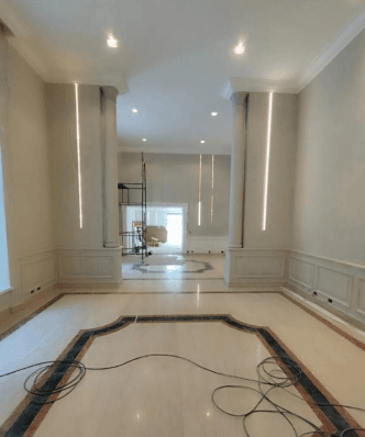 Salão com paredes em boiserie, iluminação em LED e piso de mármore com desenho geométrico