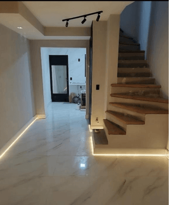 Escada com degraus de madeira, piso marmorizado e iluminação embutida em LED