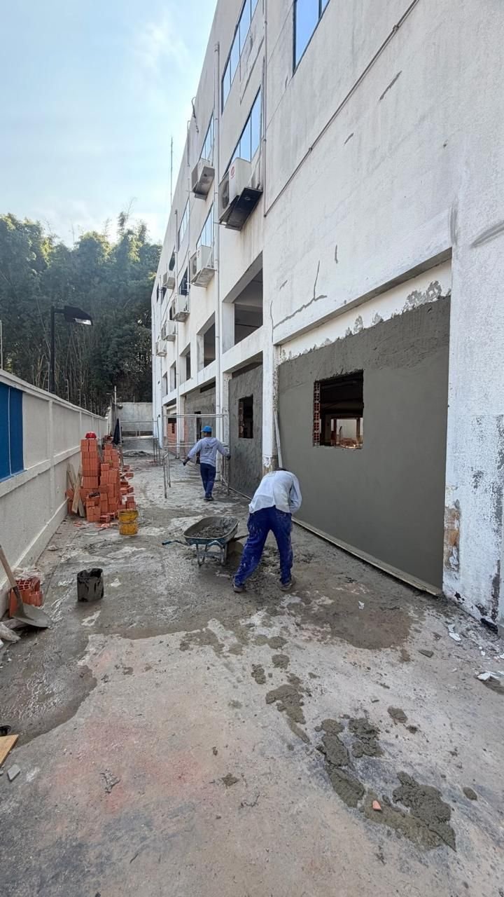 Profissionais aplicando reboco na fachada de um edifício comercial