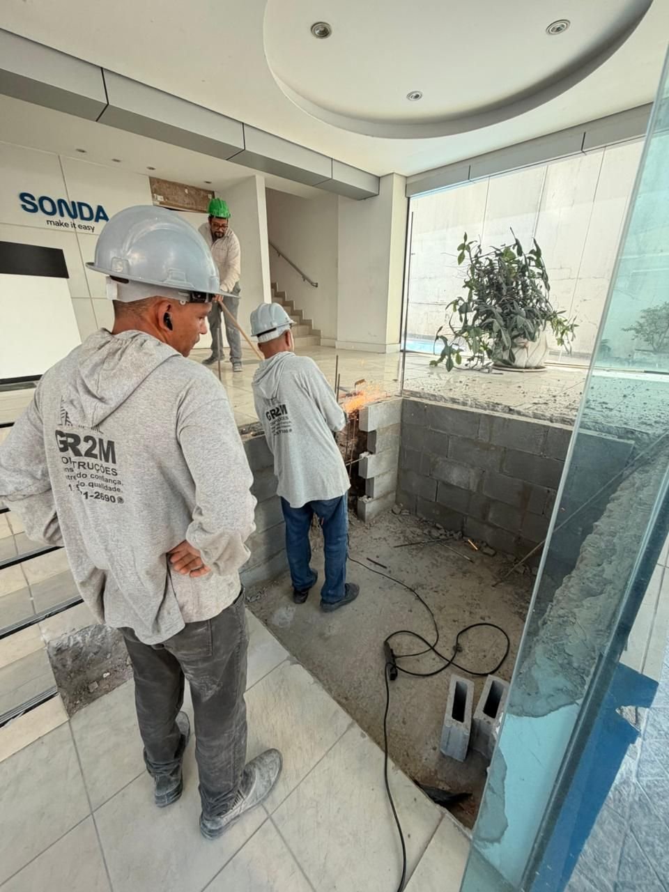 Profissionais com uniforme GR2M executando obra em recepção comercial